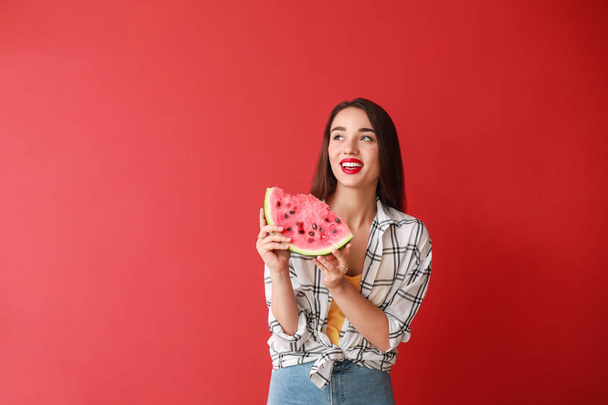 schöne junge Frau mit Scheibe frischer Wassermelone auf farbigem Hintergrund - Foto, Bild