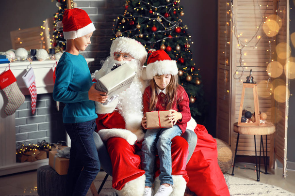Père Noël et petits enfants avec des cadeaux dans la chambre décorée pour Noël
 - Photo, image