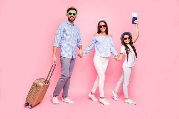 Full length photo of beautiful three people brunettes holding hands trolley wearing t-shirt plaid shirt eyewear headwear eyeglasses isolated over pink background - Foto, afbeelding