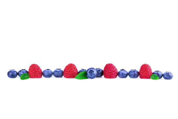 Raspberries and Blueberries in a line isolated on white. Fresh berry mix concept. - Photo, Image