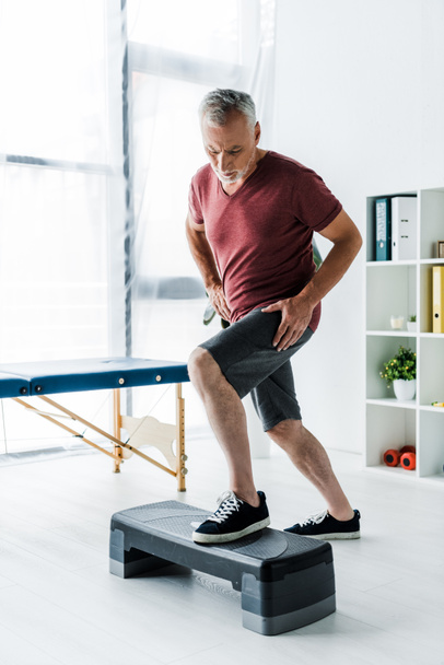 μεσαίου ηλικίας άνθρωπος άσκηση στην πλατφόρμα βήμα στην κλινική   - Φωτογραφία, εικόνα