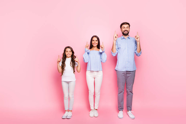 Full size photo of cheerful parents and child with wavy long haircut point at copy space wear plaid checkered shirt blouse t-shirt isolated over pink background - Foto, Bild