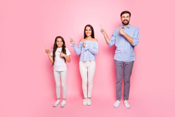 Full body photo of charming family with long wavy curly haircut pointing at copy space wearing checkered shirt trousers pants isolated over pink background - Photo, Image