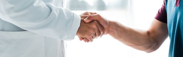 panoramic shot of doctor in white coat shaking hands with man  - Foto, Imagem