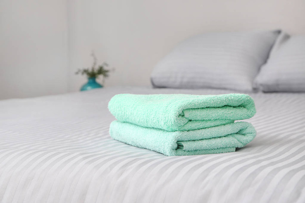 Στοίβα από καθαρές πετσέτες στο κρεβάτι - Φωτογραφία, εικόνα