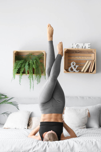 Genç kadın yatakta evde Yoga uygulamak - Fotoğraf, Görsel