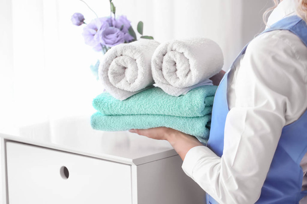 Empregada feminina colocando toalhas limpas no peito das gavetas
 - Foto, Imagem