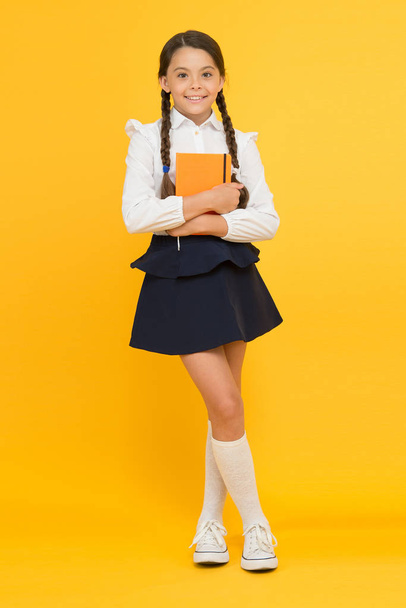 School girl formal uniform hold book. School lesson. Study literature. Towards knowledge. Learn following rules. Welcome back to school. Inspirational quotes motivate kids for academic year ahead - 写真・画像