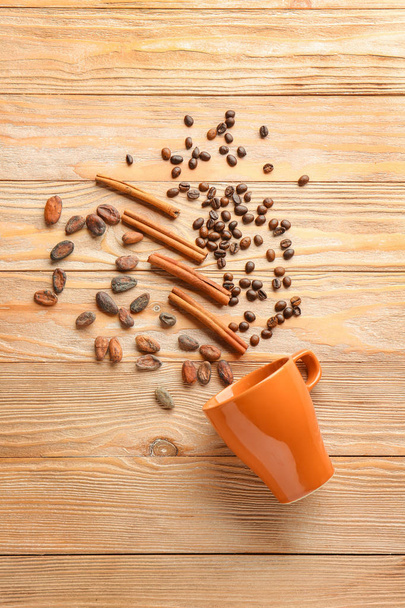 Чашка с ароматом корицы, кофе и какао бобы на деревянном фоне
 - Фото, изображение