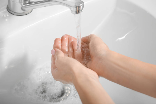 Молодая женщина моет руки в раковине
 - Фото, изображение