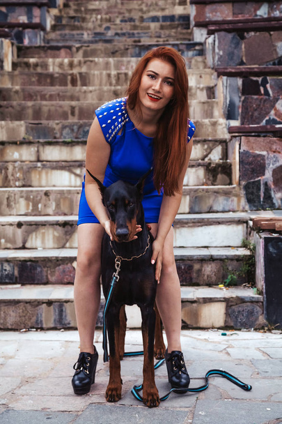 彼女の犬の黒いドーベルマン屋外で一緒に歩いて美しい女性の所有者 - 写真・画像