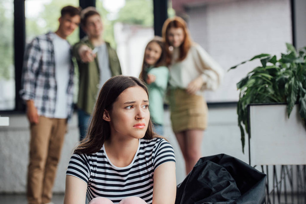 selective focus of group of teenagers bullying sad girl in school - Photo, Image