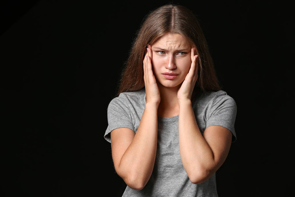 Stressed young woman on dark background - Foto, afbeelding