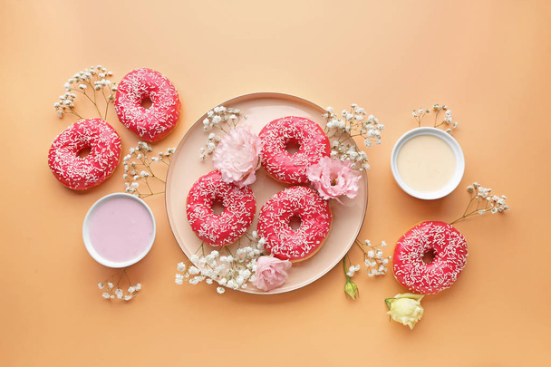 Composition with sweet tasty donuts and flowers on color background - Photo, Image
