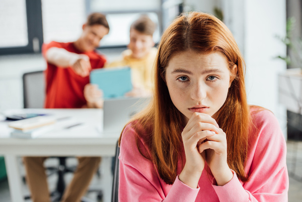sad pensive girl and classmates laughing at her in school - Photo, Image