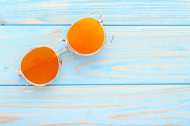 Modern sunglasses on blue wooden table - 写真・画像