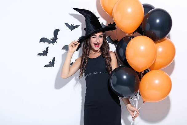 Young woman in halloween costume with balloons on white background - Foto, imagen