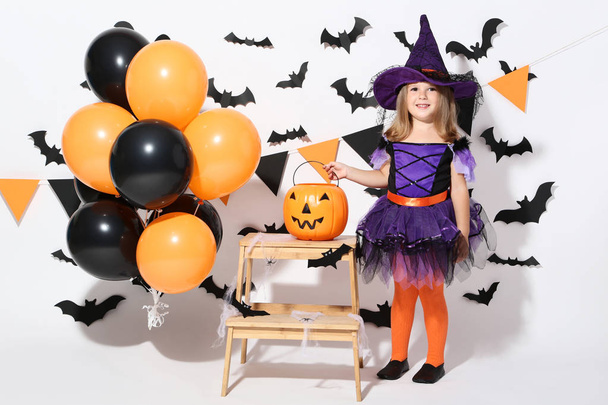 Young girl in halloween costume with balloons and pumpkin bucket - Foto, Imagen