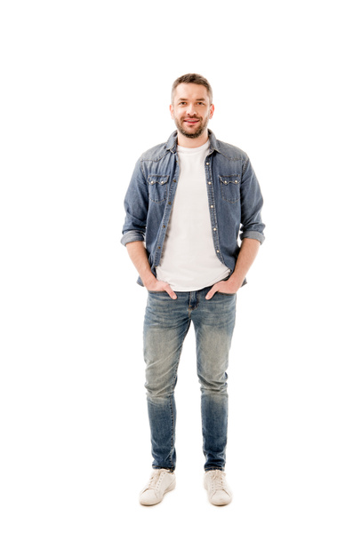 vista completa de hombre barbudo sonriente en jeans de pie con las manos en bolsillos aislados en blanco
 - Foto, Imagen