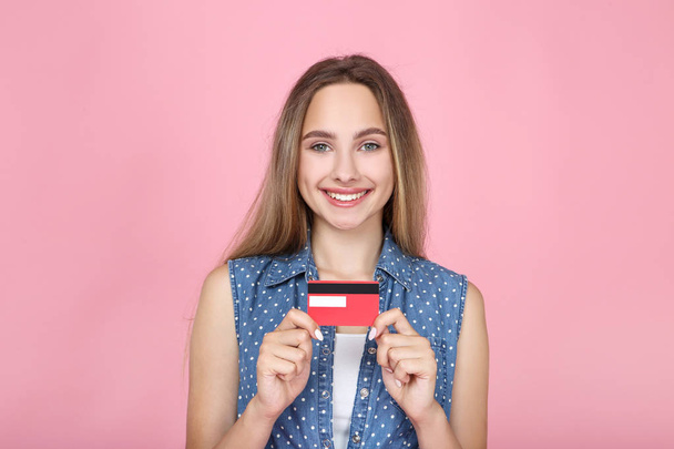 Beautiful young woman holding credit card on pink background - Фото, изображение