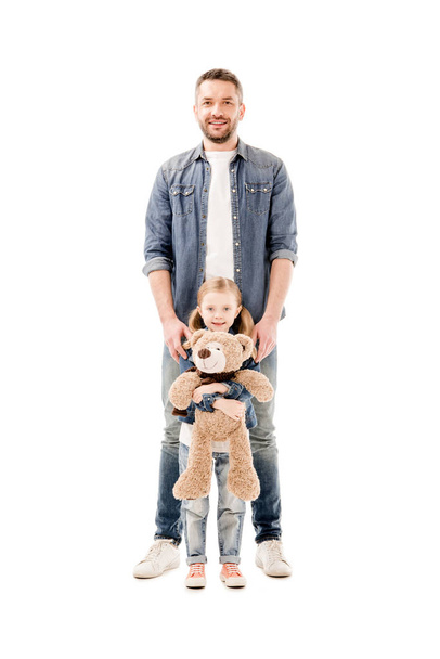 full length view of smiling dad in jeans and daughter with teddy bear isolated on white - Photo, Image