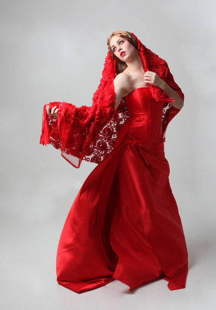 Pełna długość Portret dziewczyny ubrana w długą czerwoną suknię jedwabną, stojący stwarzają na szarym tle Studio. - Zdjęcie, obraz