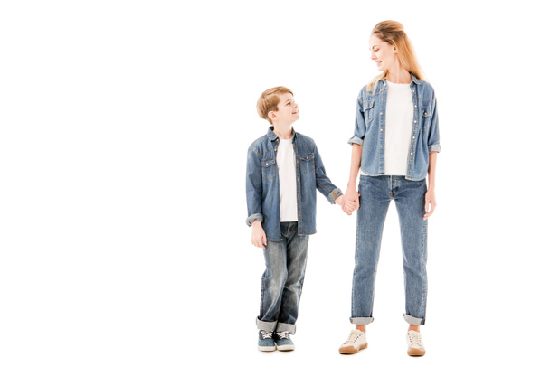 full length view of happy mother and son holding hands and looking at each other isolated on white - Φωτογραφία, εικόνα