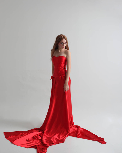 uzun kırmızı ipek gece elbisesi giyen bir kızın tam uzunlukta portre, Gri bir stüdyo arka plan üzerinde ayakta poz. - Fotoğraf, Görsel