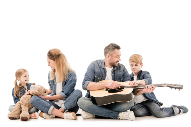 happy family in jeans with teddy bear and acoustic guitar sitting isolated on white - Photo, Image