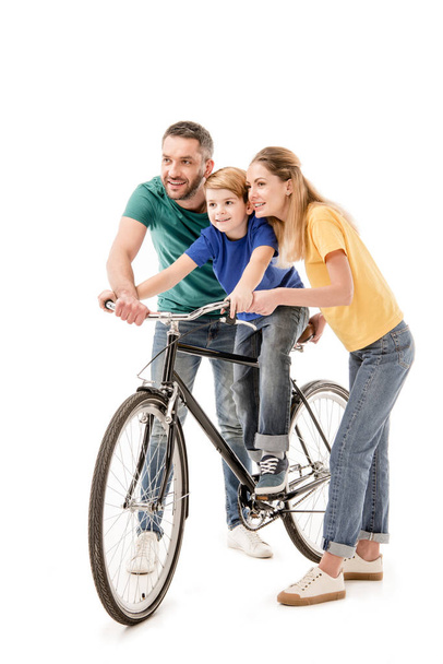 full length view of smiling parents teaching son to ride bike isolated on white - Fotó, kép