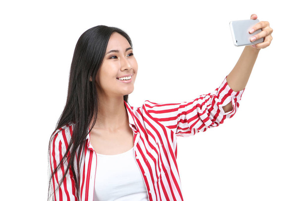 Young woman making selfie on smartphone on white background - Φωτογραφία, εικόνα