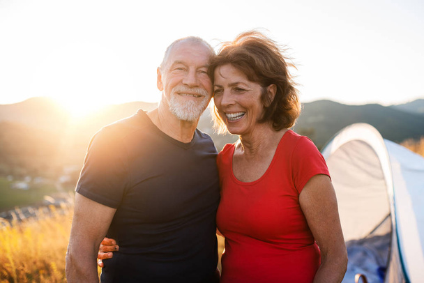 Senior tourist couple standing in nature at sunset, resting. - 写真・画像
