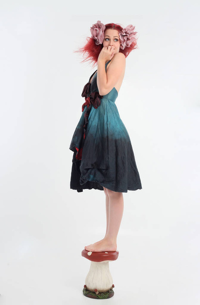 портрет рыжеволосой девушки в сказочном костюме, позирующей на белом фоне студии
. - Фото, изображение