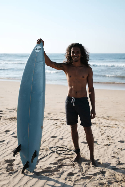 Man Surfer Sitting at Surfboard on Sand Beach - Foto, immagini