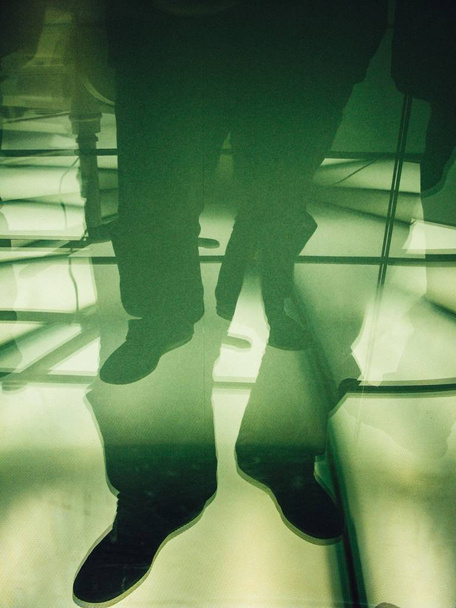 Vertical double exposure photography of male feet on a glassy surface - Fotografie, Obrázek