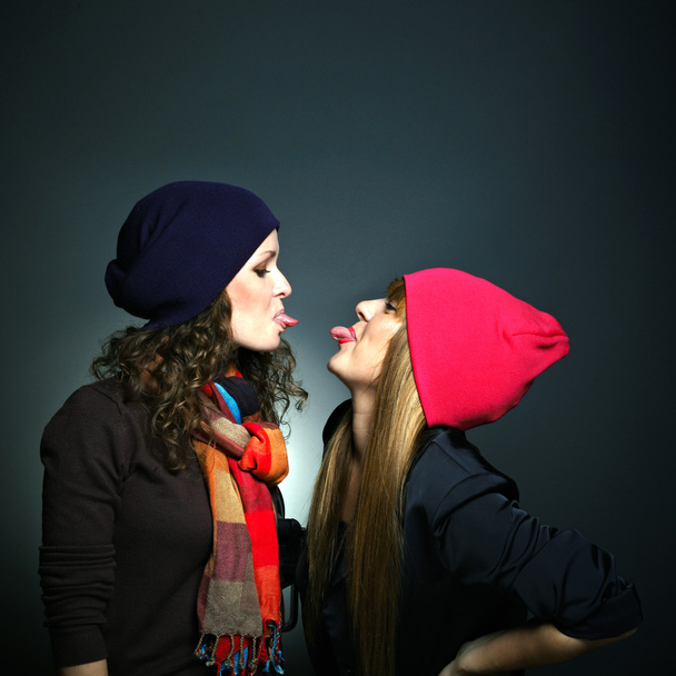 Portrait of two female friends in playful mood against grey background - Photo, image