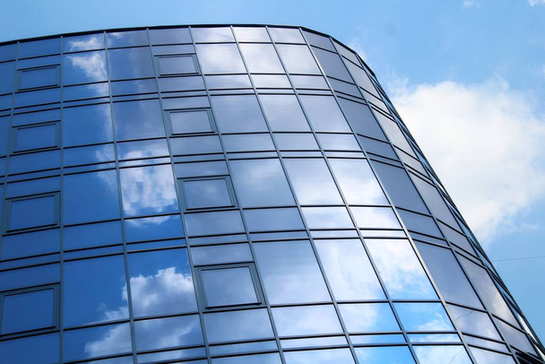 Облака отражаются во многих зеркальных фасетах современного офисного здания
 - Фото, изображение