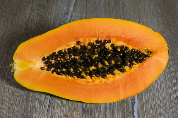 Frissen szeletelt papaya, maggal, fa háttéren - Fotó, kép