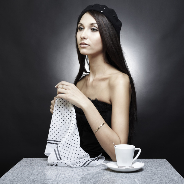 Portrait of the sitting young beautiful woman-brunette behind a table - Фото, зображення