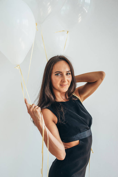 Cute brunette woman standing smiling and playing with balloons. - Fotoğraf, Görsel