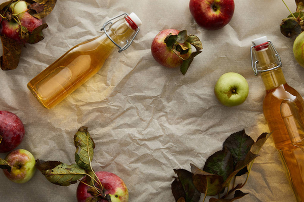 vista dall'alto di bottiglie con sidro vicino a mele sparse e foglie
 - Foto, immagini