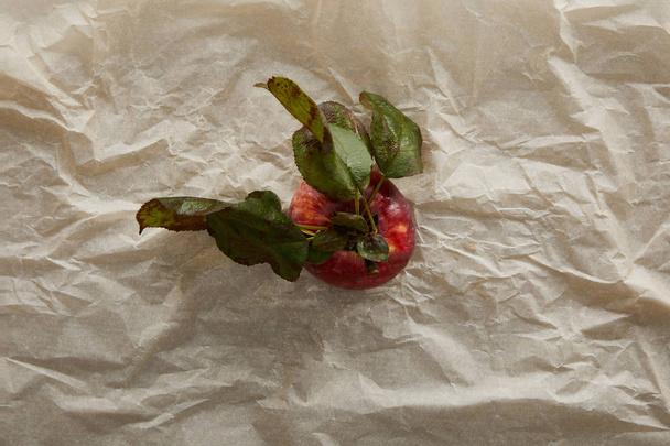 Draufsicht auf Apfel mit Blättern auf Pergamentpapier mit Kopierraum - Foto, Bild