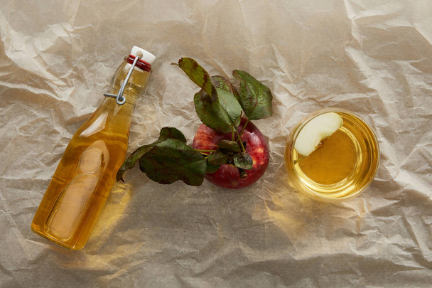 top view of apple, bottle and glass of fresh cider on parchment paper with copy space - Foto, immagini