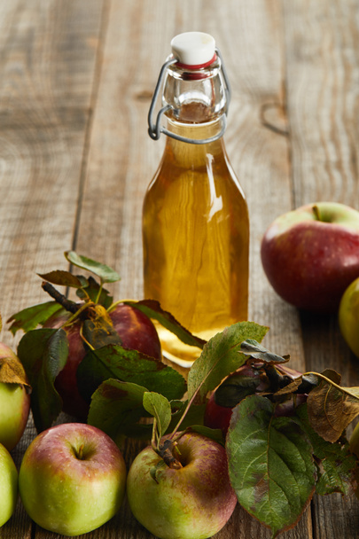 bottle of fresh cider near apples on wooden surface - Photo, image