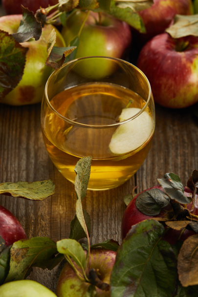 glass of fresh cider with slice near apples on wooden surface - Fotoğraf, Görsel