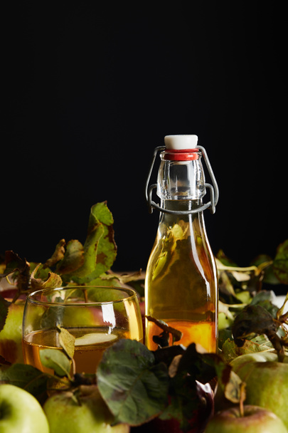 bottle and glass of fresh cider near ripe apples isolated on black - Foto, Imagem