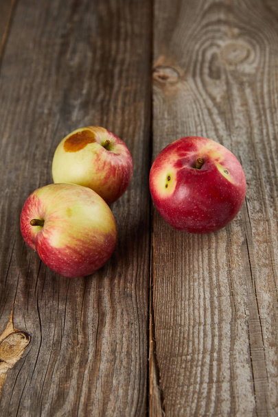 farmers apples with small rotten spot on brown wooden surface with copy space - Photo, Image
