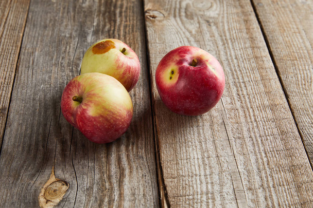 Bauern Äpfel mit kleinen faulen Flecken auf brauner Holzoberfläche - Foto, Bild