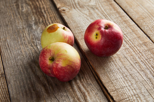 farmers apples with rotten spot on brown wooden surface - Photo, Image