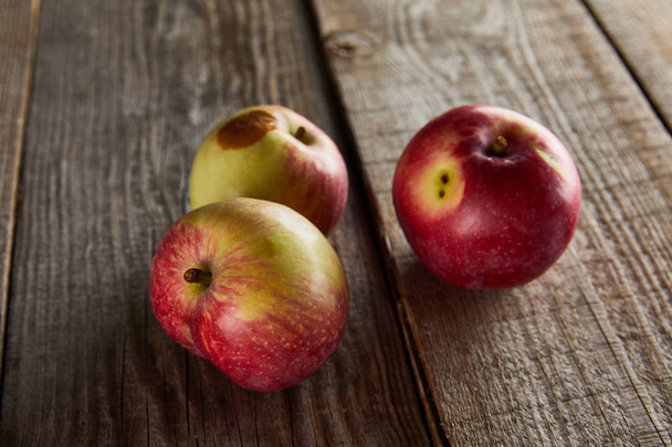 appels met kleine rot vlek op bruin houten oppervlak - Foto, afbeelding